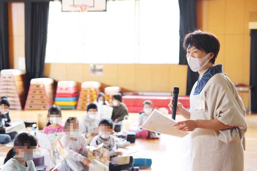 福岡市内の小学校での博多人形絵付け体験教室です。講師の伝統工芸士（博多人形）の緒方恵子が絵付けの方法などを説明しています。